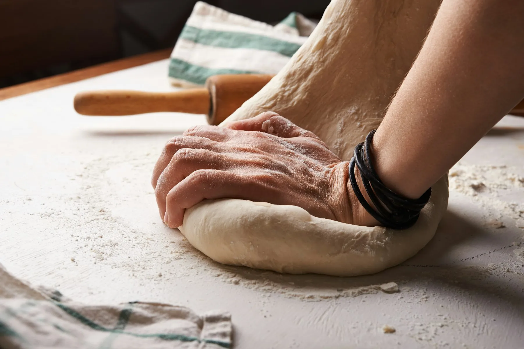Mains d'un boulanger travaillant la pâte sur un plan fariné